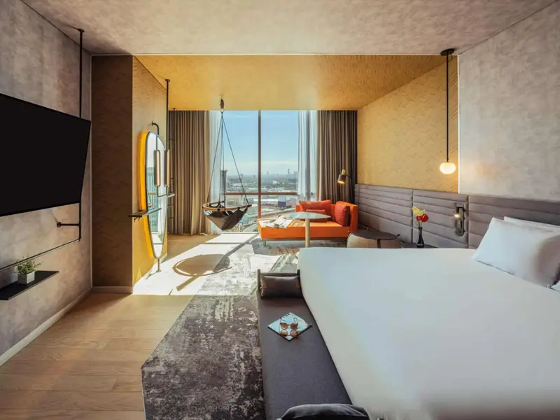 Une chambre lumineuse avec un grand lit et un coin salon près d'une fenêtre.