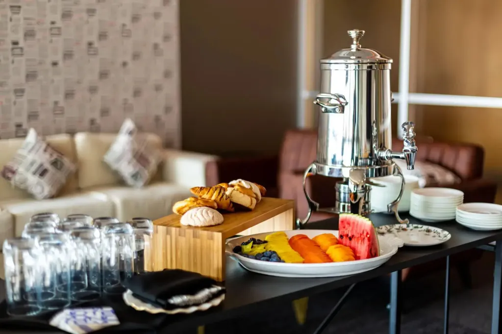 Un buffet propose des fruits frais, des viennoiseries et des boissons.