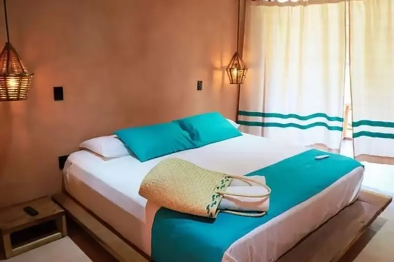 Une chambre lumineuse avec un grand lit recouvert d'une courtepointe turquoise.
