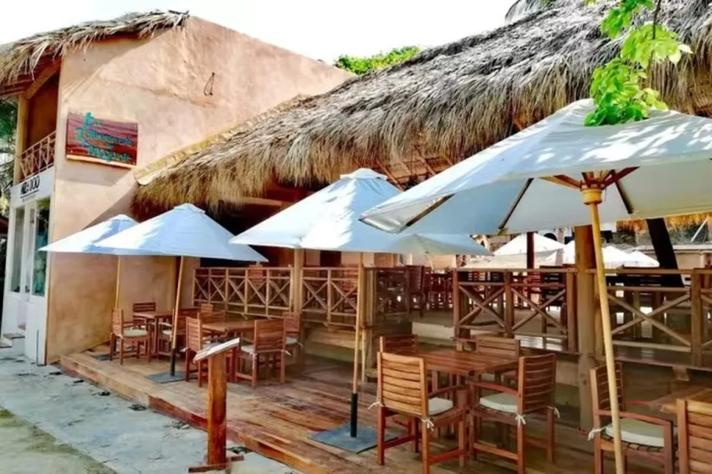 Terrasse ombragée avec tables et chaises en bois.