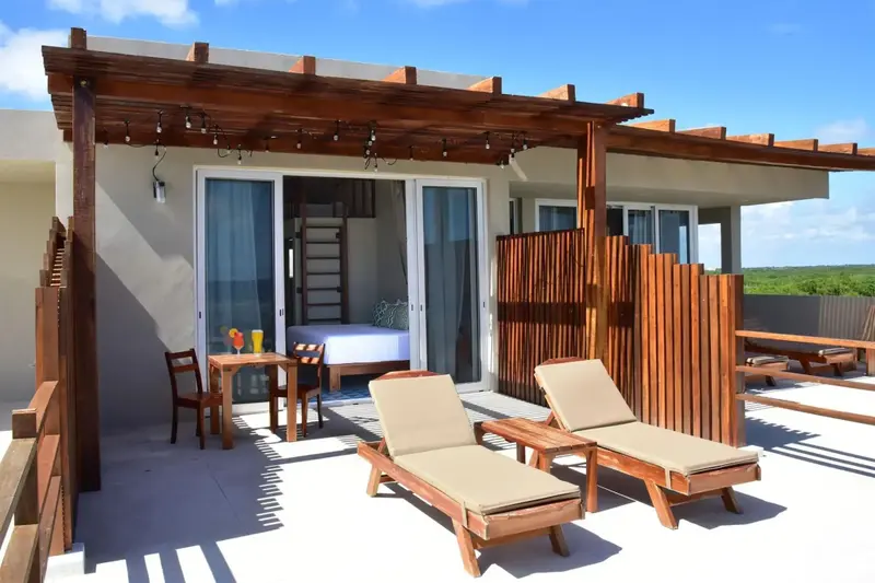 Terrasse aménagée avec salon de jardin et accès à une chambre.