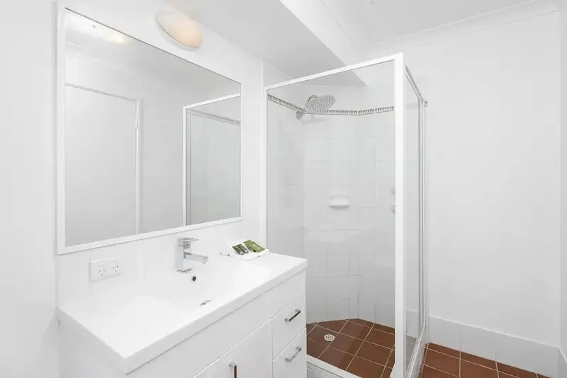 Une salle de bain lumineuse avec douche et vasque.