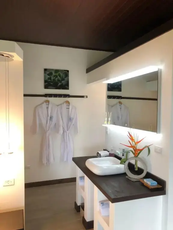 Une salle de bain lumineuse avec des peignoirs blancs suspendus.