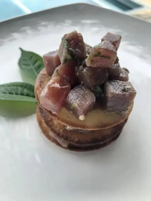 Assiette présentée avec une préparation à base de poisson cru et d'herbes fraîches.