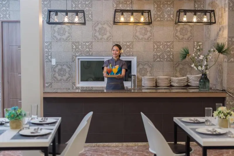 Une employée souriante sert des boissons colorées dans un espace de restauration lumineux.