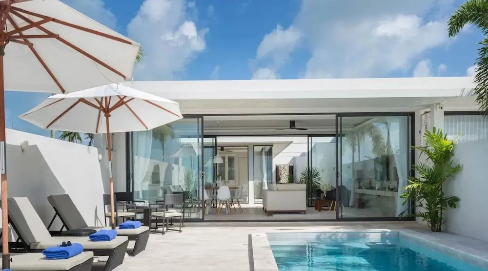 Terrasse avec transats et piscine devant un espace de vie lumineux.