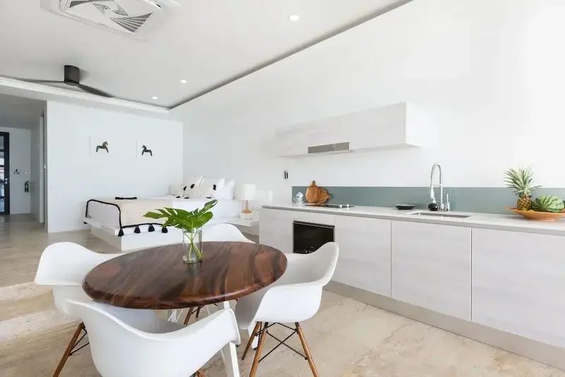 Une pièce lumineuse combine un espace repas avec une cuisine équipée et un coin chambre.