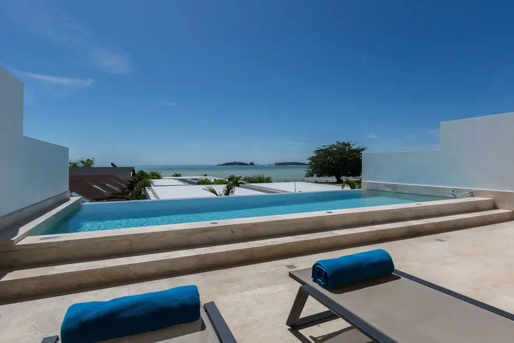 Une piscine à débordement offre une vue sur la mer et une île au loin.