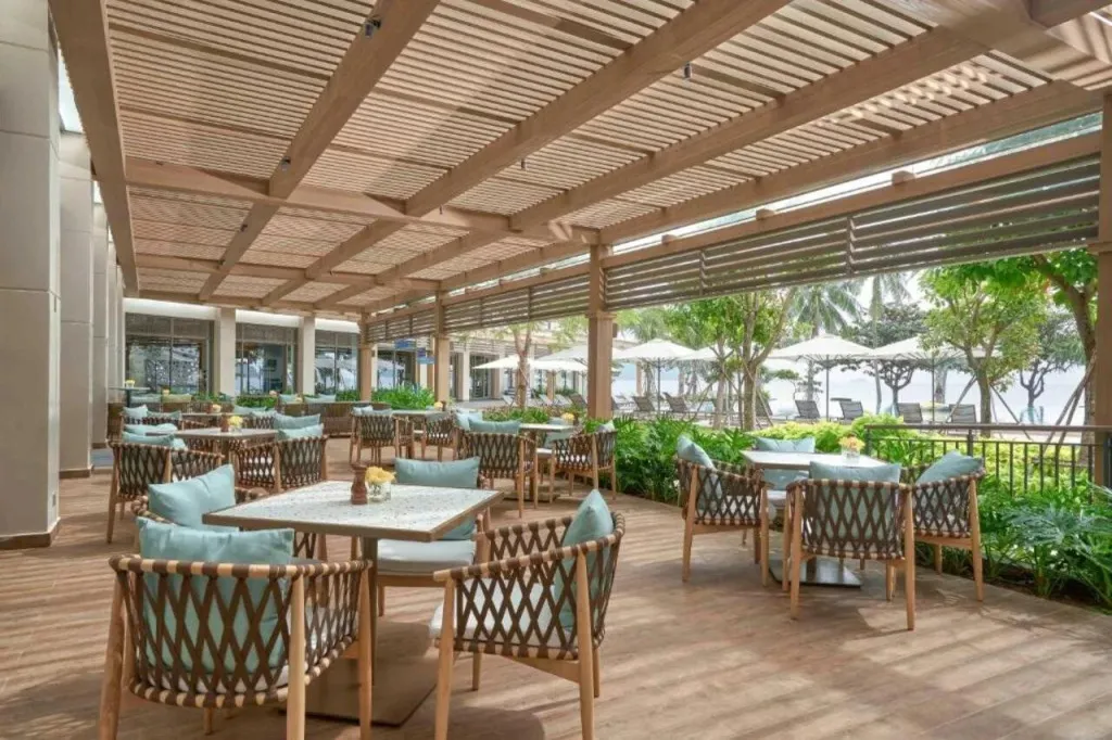 Terrasse ombragée avec tables et chaises pour les repas.