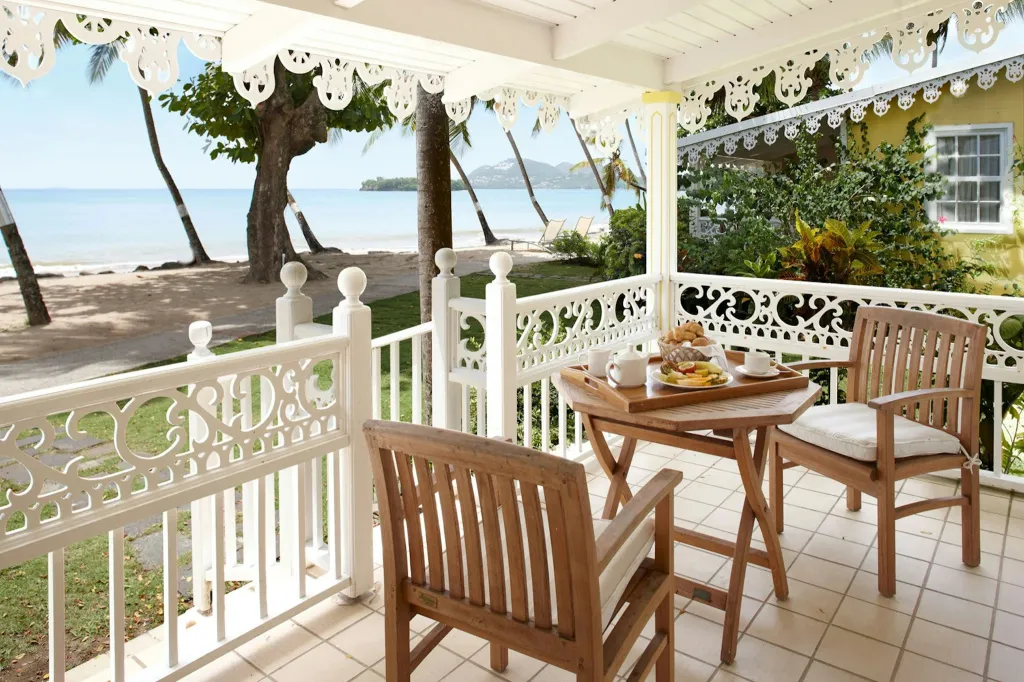 Une table est dressée avec un petit-déjeuner sur une terrasse ombragée avec vue sur la mer.