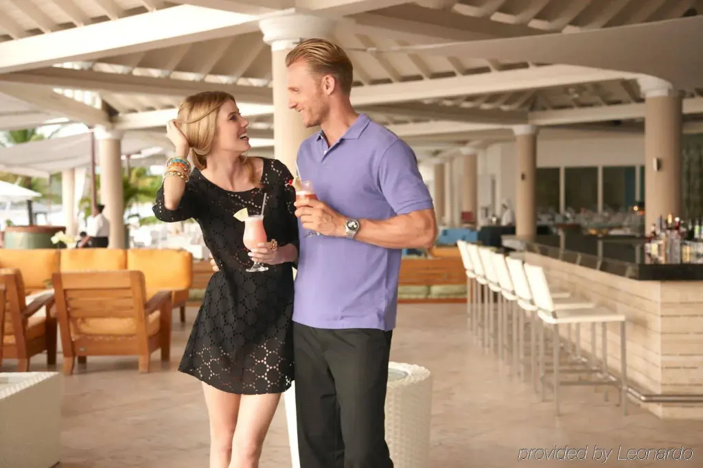 Un couple souriant déguste des boissons dans un espace extérieur ombragé.