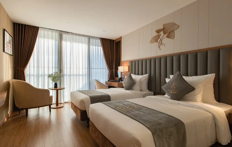 Une chambre lumineuse avec deux lits simples et un fauteuil.