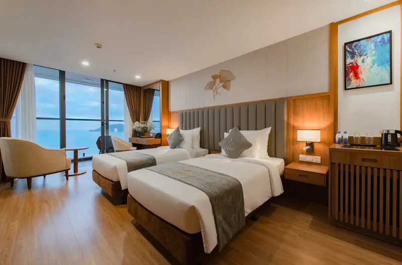 Chambre lumineuse avec deux lits et vue sur la mer.