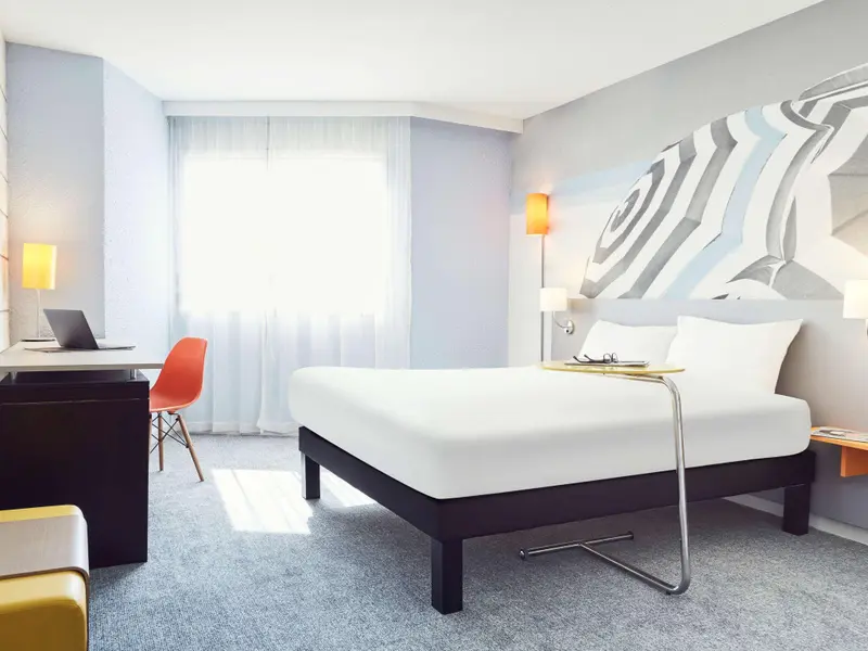 Une chambre moderne avec un lit blanc et un bureau.