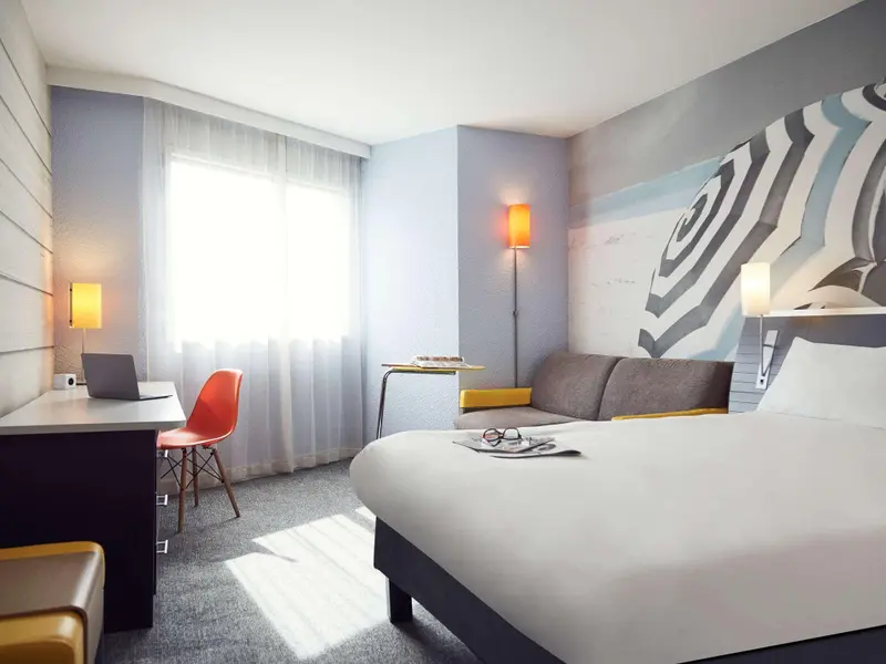 Une chambre lumineuse avec un bureau, un lit et un canapé.
