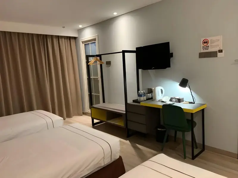 Une chambre d'hôtel lumineuse avec deux lits et un bureau.
