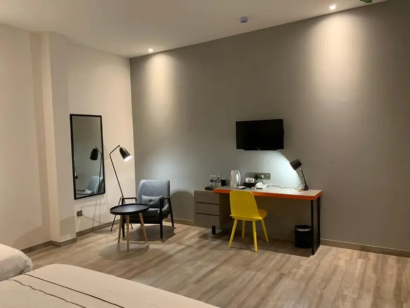 Une chambre lumineuse avec un coin salon et un bureau.