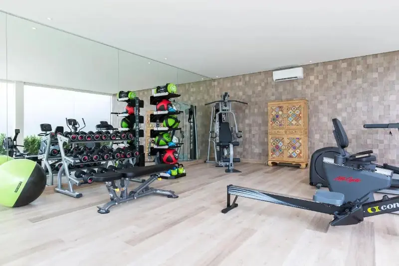 Une salle de sport lumineuse avec divers équipements de musculation et un grand miroir.