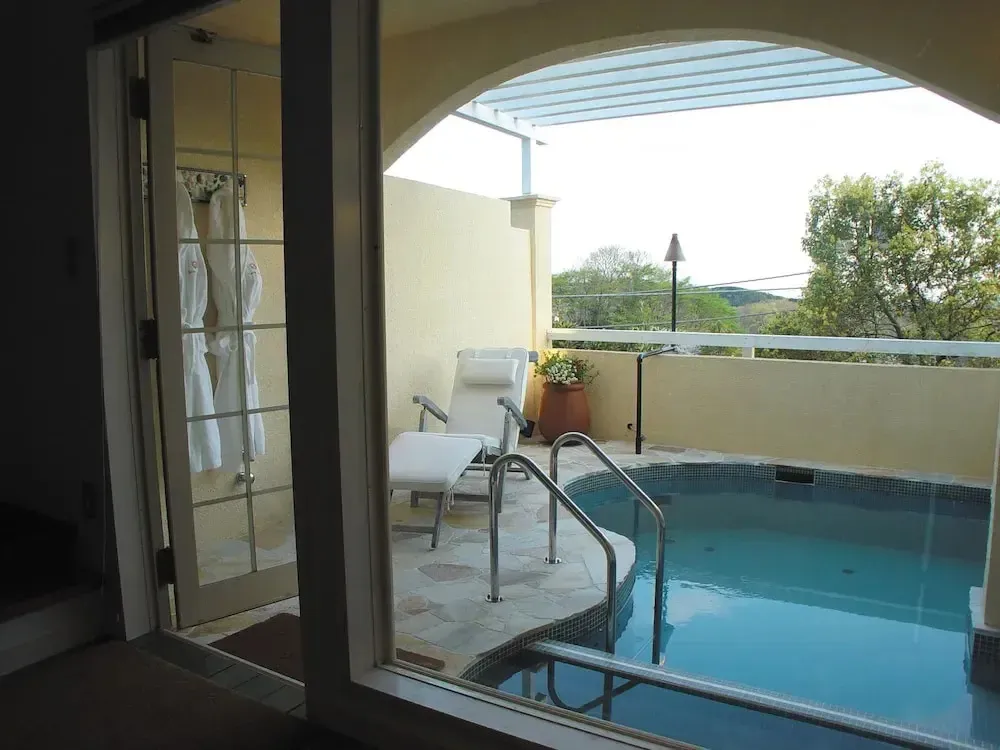 Une piscine privée avec transats sur une terrasse ombragée.
