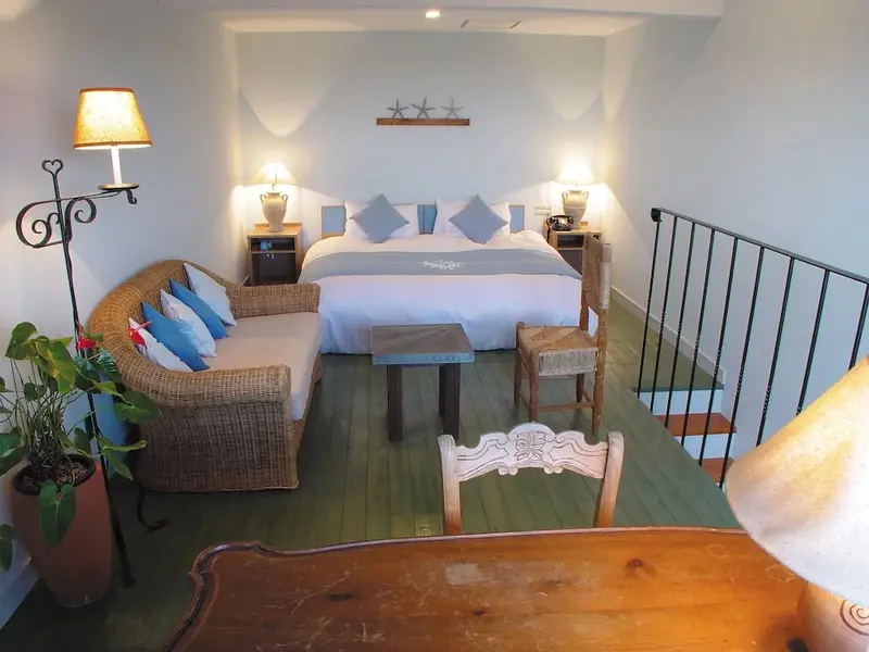 Une chambre lumineuse avec un lit double et un coin salon.