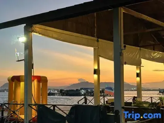 Terrasse ombragée donnant sur la mer au coucher du soleil.