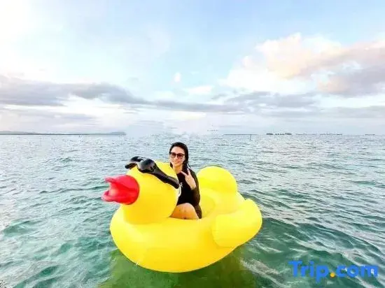 Une personne assise sur un canard gonflable jaune en mer.