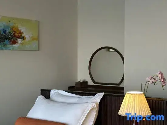 Une chambre lumineuse avec un lit et un miroir au-dessus d'une commode.