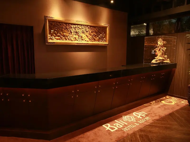 Un comptoir d'accueil en bois sombre est décoré d'un panneau sculpté et d'un aquarium.