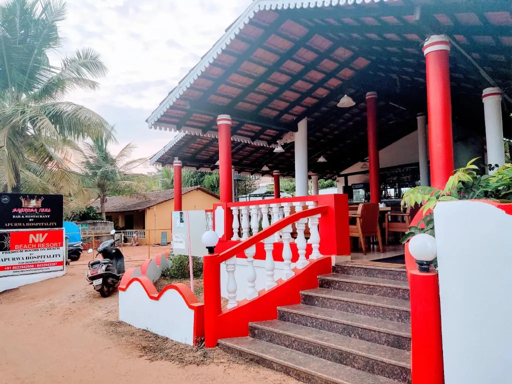 Entrée d'un restaurant avec des colonnes rouges et des escaliers.