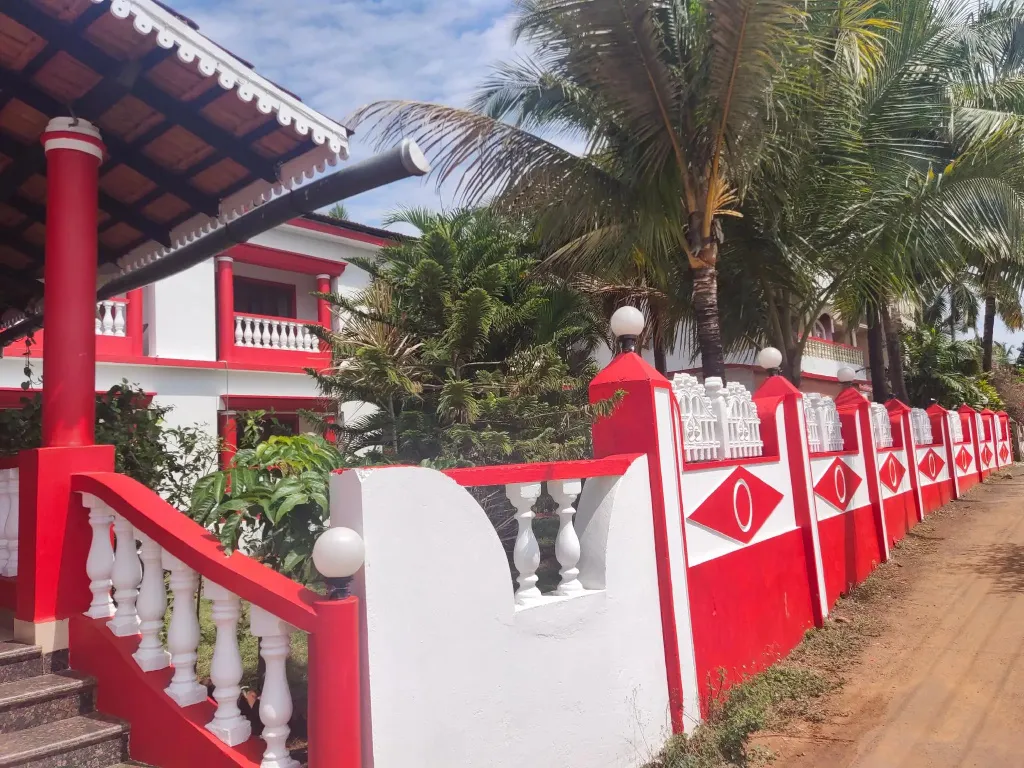 Facade d'un bâtiment blanc et rouge avec un escalier et des palmiers.