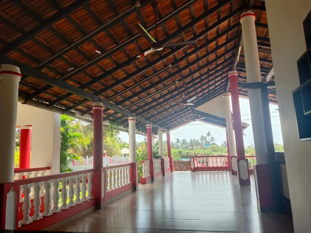 Terrasse couverte avec colonnes et vue sur la végétation.