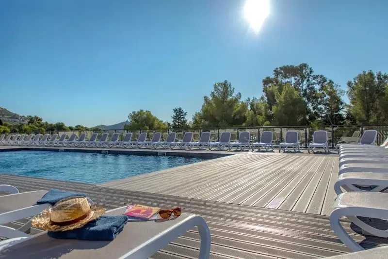 Transats alignés au bord d'une piscine ensoleillée.