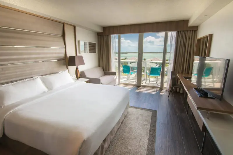 Une chambre lumineuse avec un grand lit et un accès à une terrasse offrant une vue sur la mer.