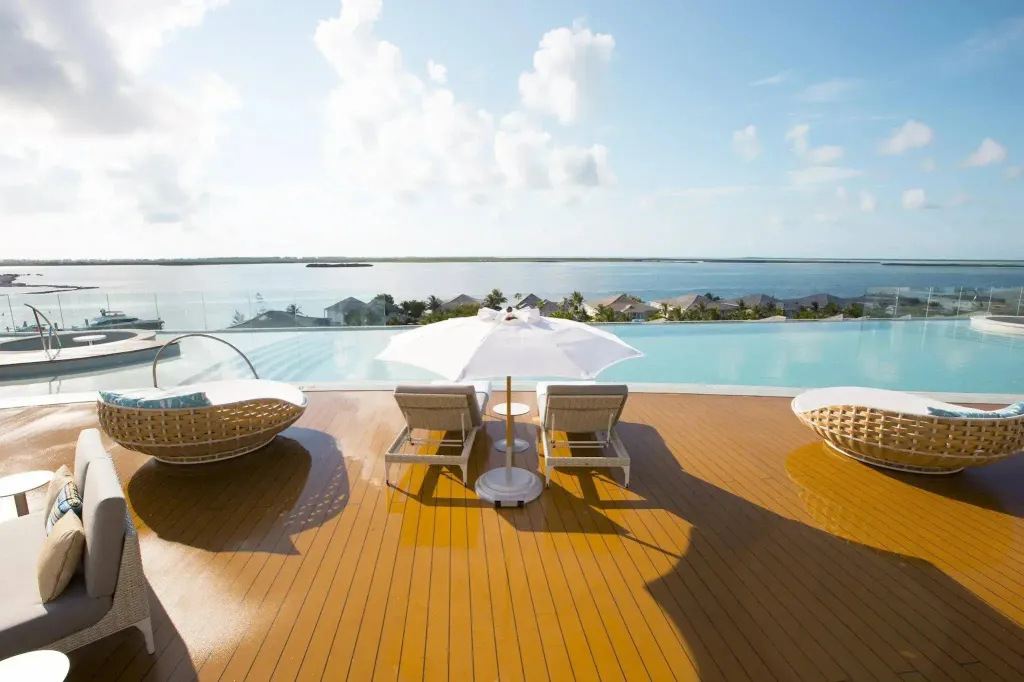 Terrasse avec transats et piscine à débordement donnant sur la mer.