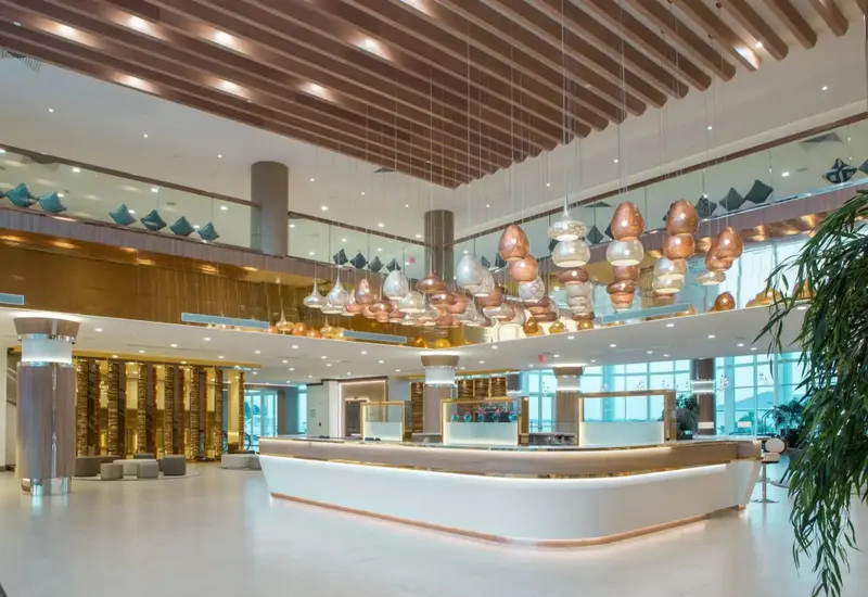 Vaste hall d'accueil avec un comptoir incurvé et des luminaires décoratifs.