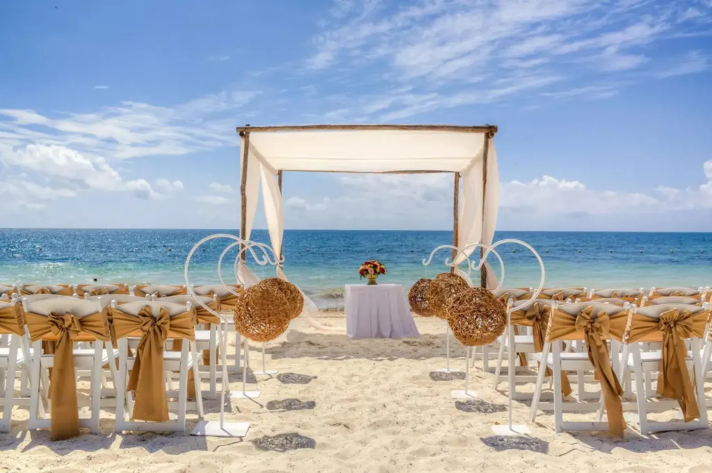 Arche nuptiale sur une plage de sable blanc face à la mer turquoise.