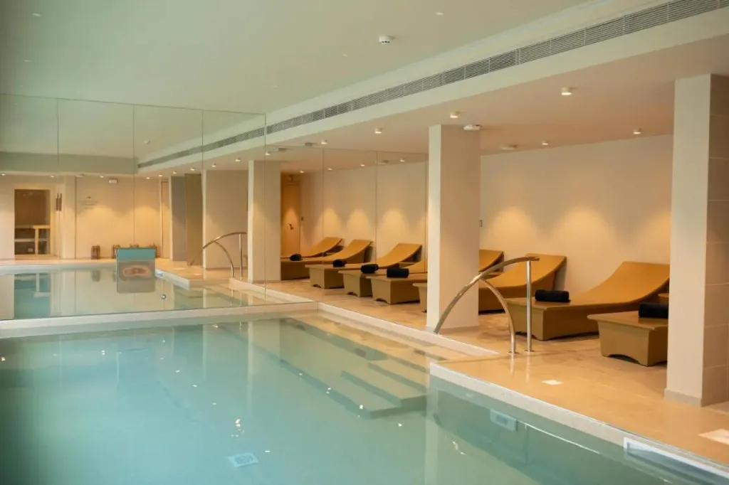 Une piscine intérieure avec des transats alignés le long d'un mur.