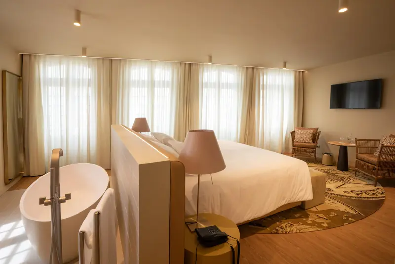 Une chambre lumineuse avec un grand lit et une baignoire.