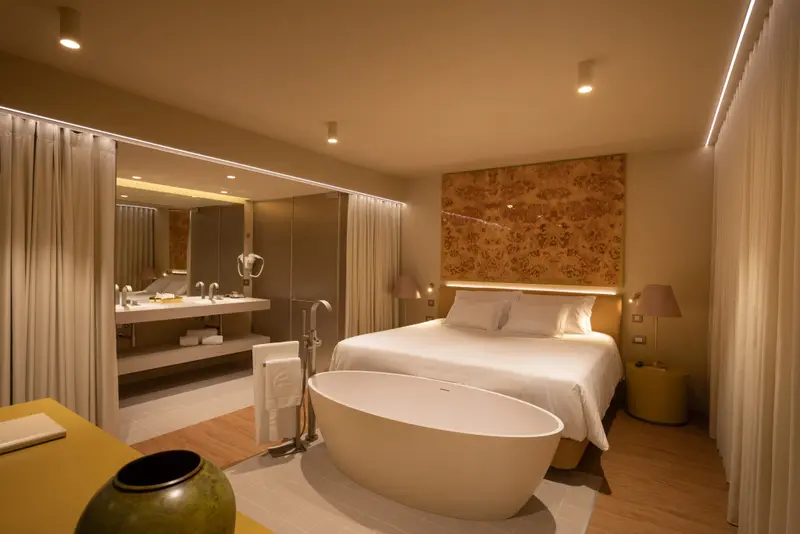 Une chambre lumineuse avec un grand lit et une baignoire îlot.