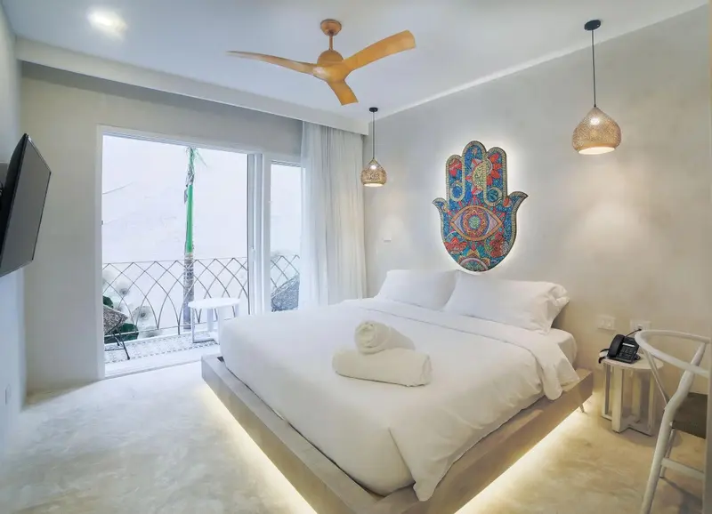 Chambre lumineuse avec un grand lit et un accès à une terrasse.