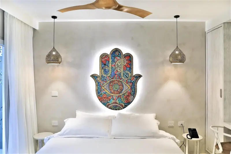 Une chambre lumineuse avec un grand lit et une décoration murale colorée.